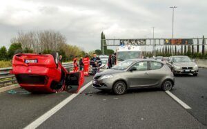 Multi-vehicle car accident with an overturned red car on a highway, the type of car accident case handled by Aulsbrook Car & Truck Wreck Injury Lawyers Arlington