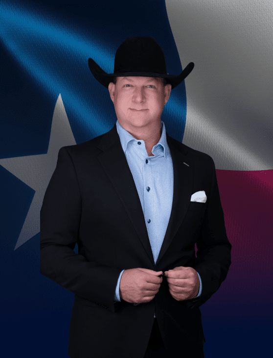 Attorney at Aulsbrook Car & Truck Wreck Injury Lawyers Fort Worth wearing a black cowboy hat and suit in front of the Texas flag